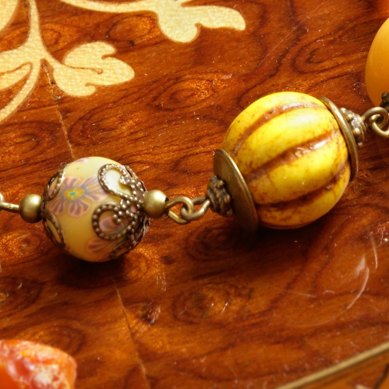 Armband Bernsteinschatz, Nahaufnahme einer Millefiori-Kugel aus Polymer Clay und der "Kürbis"-Perle aus gefärbtem Howlith