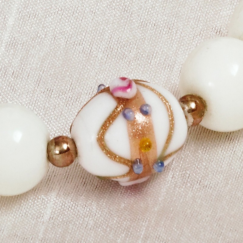 Armband Wedding Cake, Nahaufnahme einer verzierten "Wedding Cake"-Perle neben roségoldenen Metall- und weißen Glasperlen